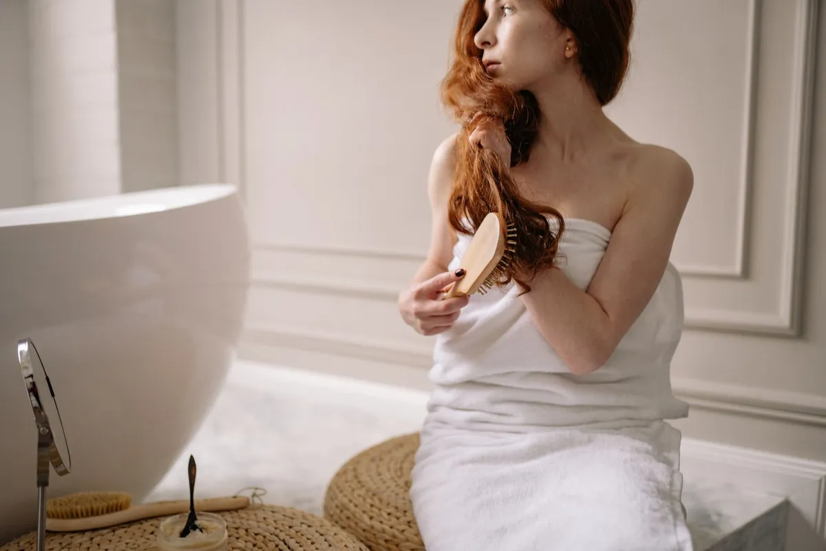 Mujer secándose el pelo frente al espejo del baño