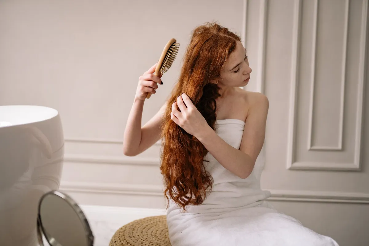Donna che si asciuga i capelli davanti allo specchio del bagno