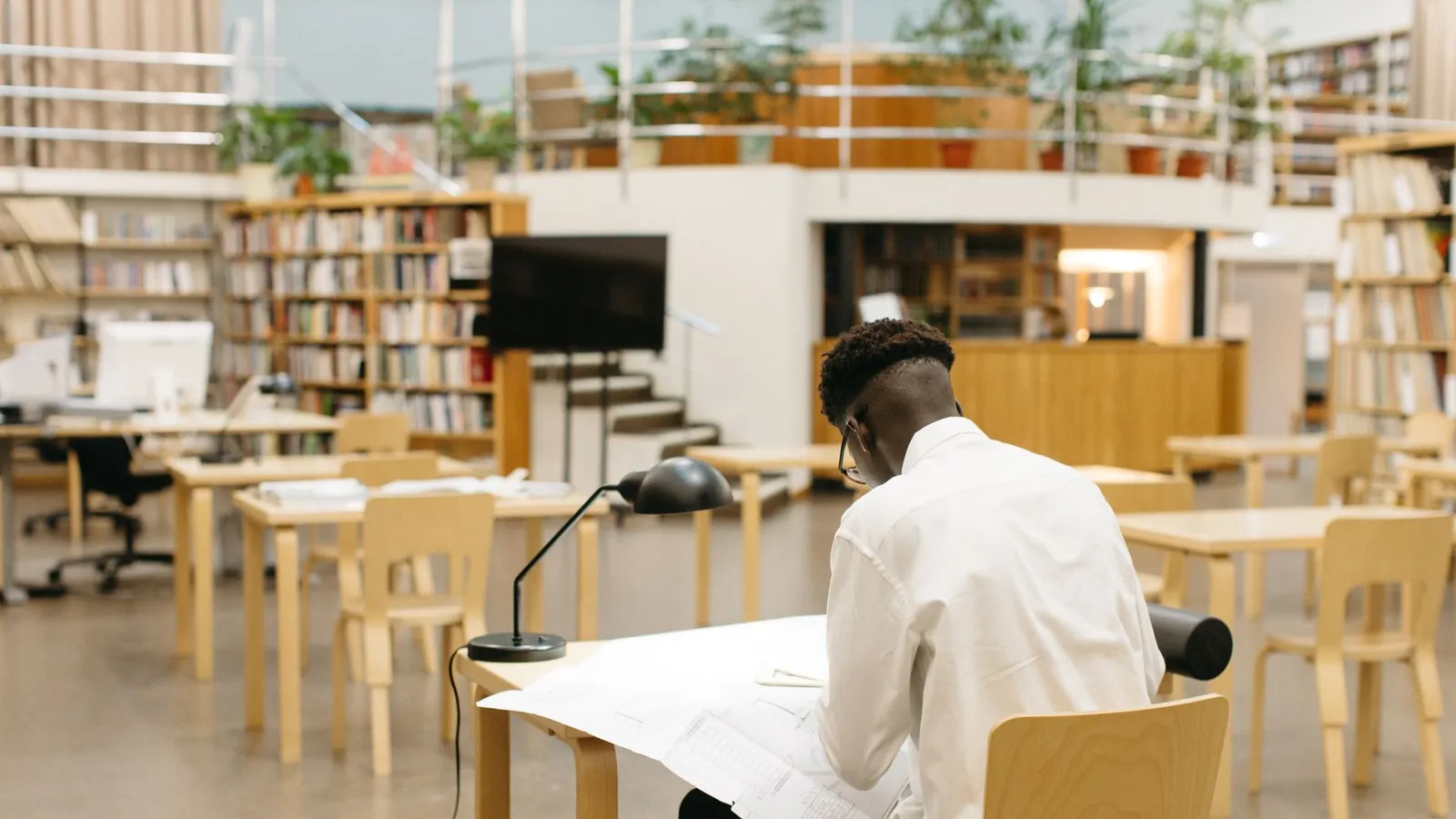 Studente con cuffie over-ear davanti a un computer portatile su una scrivania