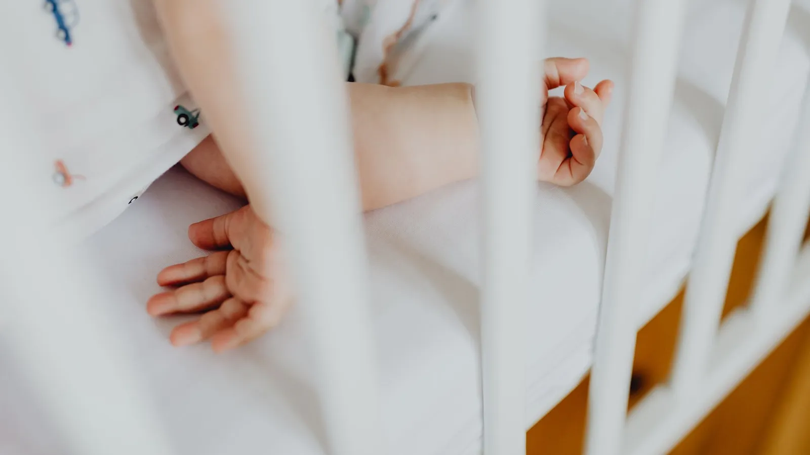 Neonato che dorme nel lettino di una cameretta con luce bassa