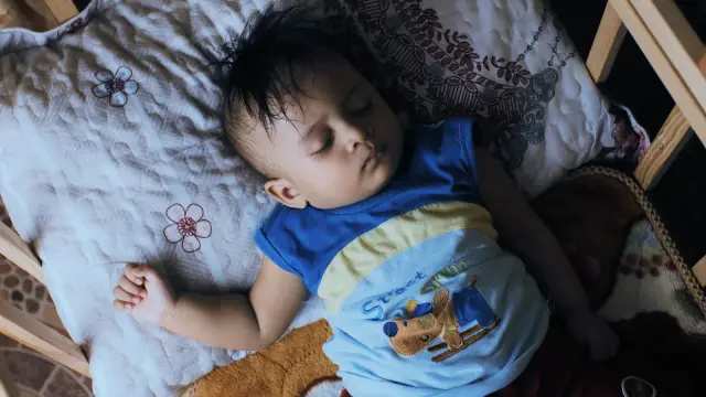 A baby asleep in a crib in a dim nursery