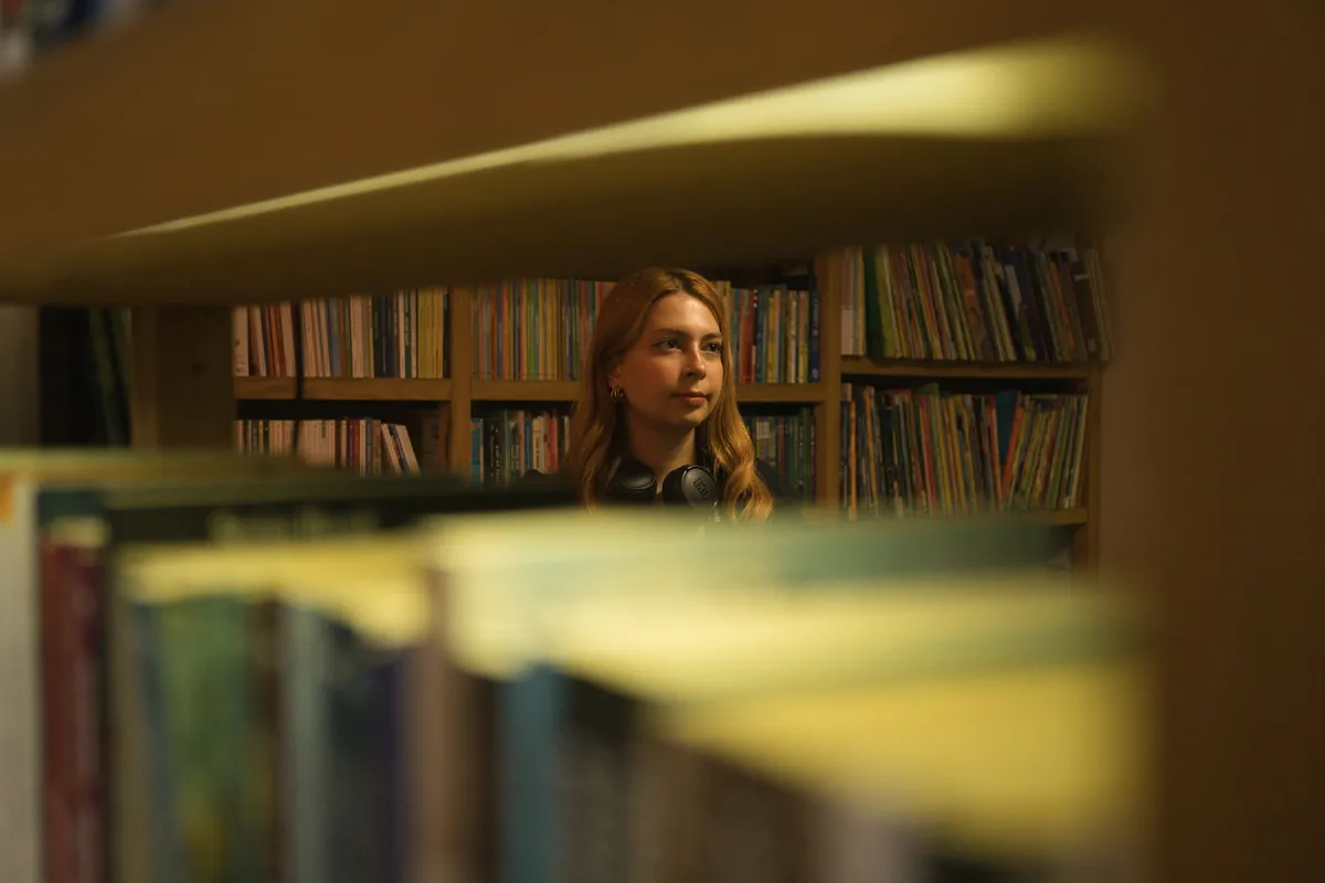 Student wearing over-ear headphones at a library table