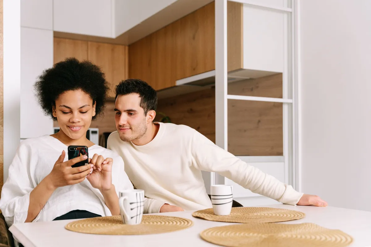 Someone comparing prices on a phone in a kitchen