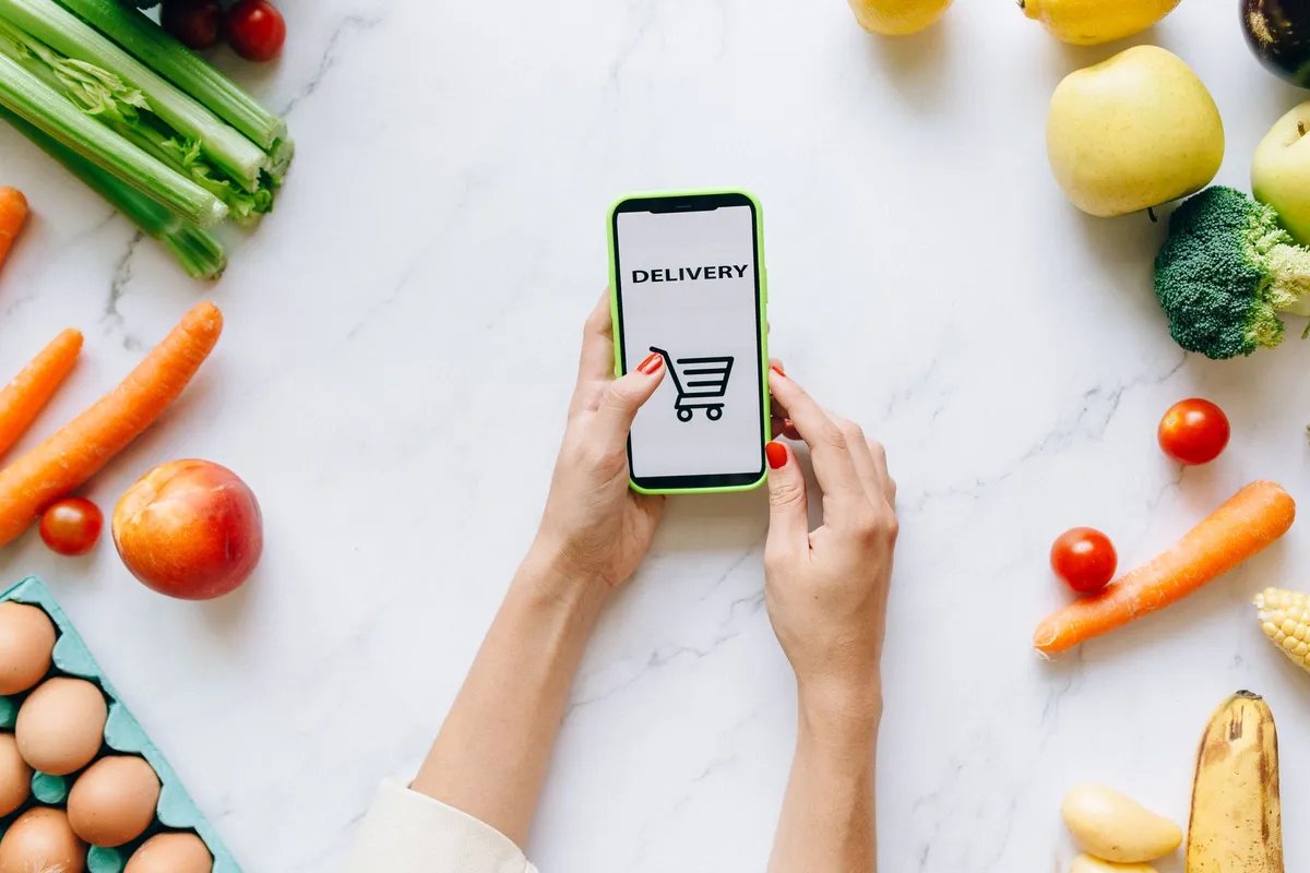 Persona che confronta prezzi sullo smartphone in cucina