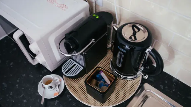 Friggitrice ad aria compatta su un piano di lavoro stretto accanto a un bollitore