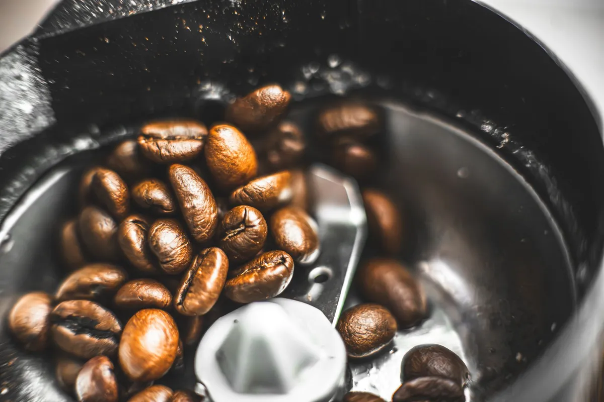 Granos de café junto a un molinillo