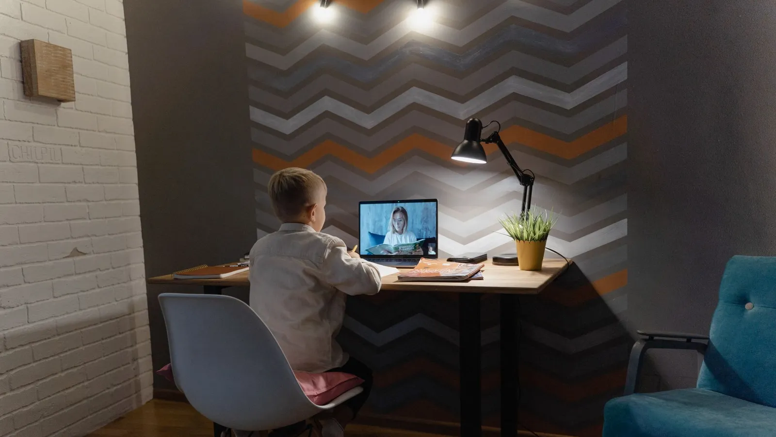 Ragazzo che fa i compiti davanti a un monitor su una scrivania