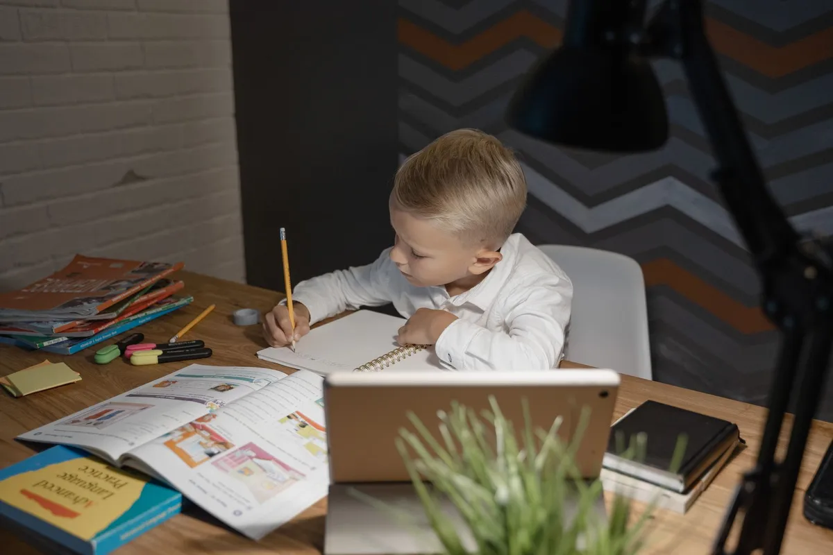 Scrivania con monitor, lampada e quaderni