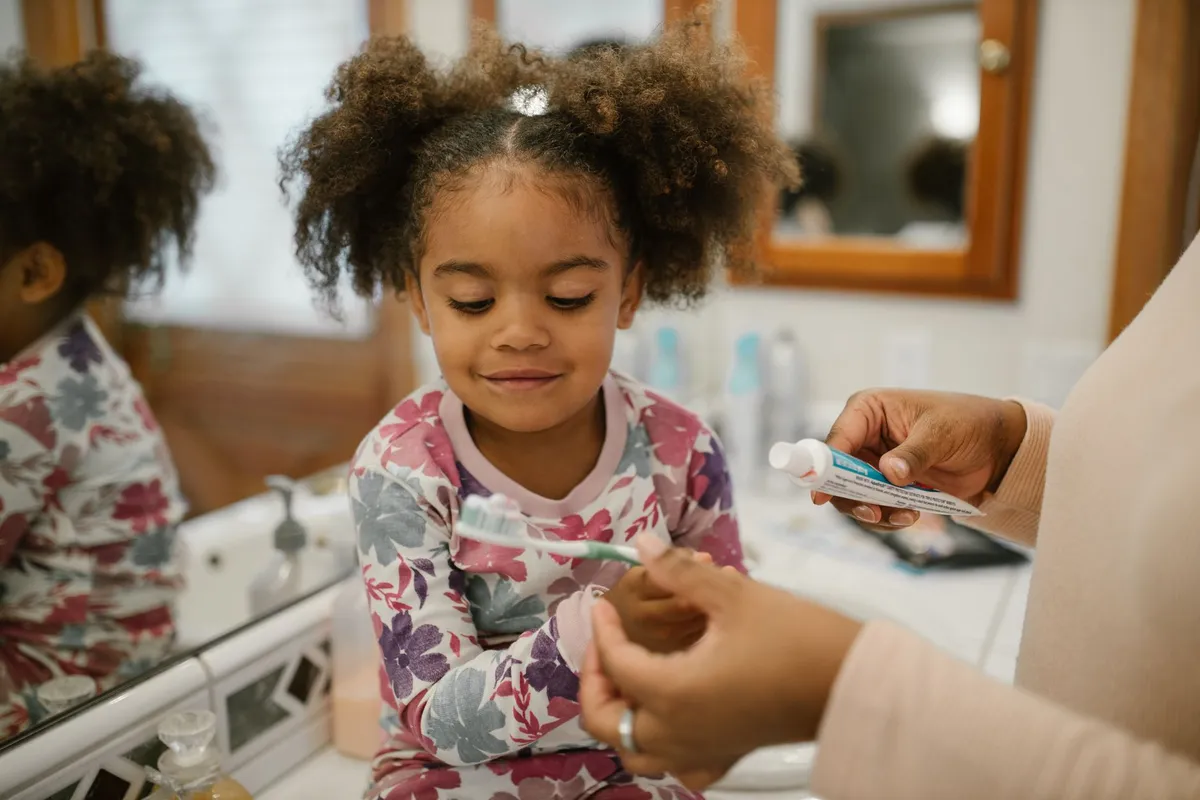 Child brushing their teeth in front of a bathroom mirror