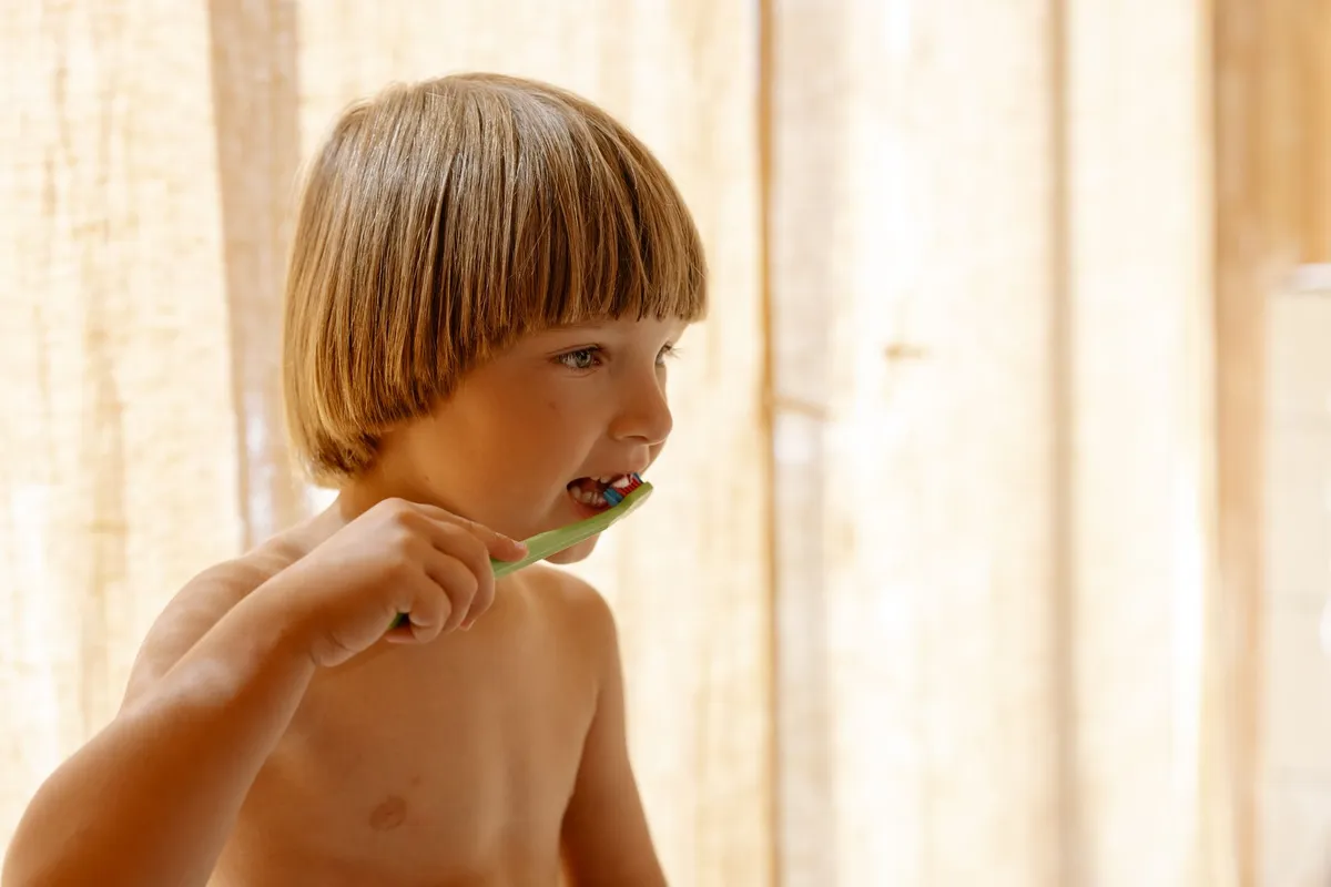 Niño cepillándose los dientes frente al espejo del baño