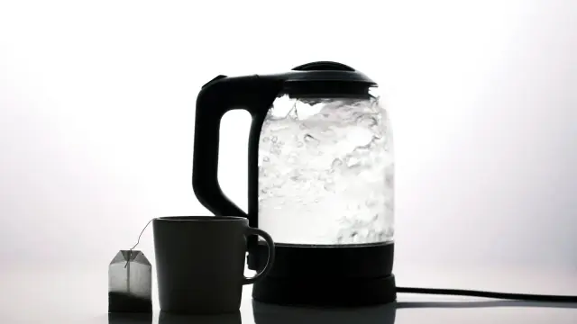Bollitore elettrico in acciaio su un piano di lavoro, accanto a una tazza di tè