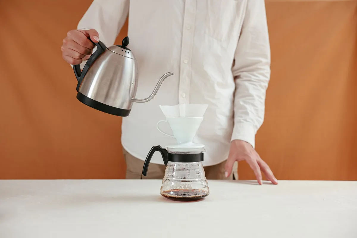 Hot water poured from a gooseneck kettle over coffee grounds