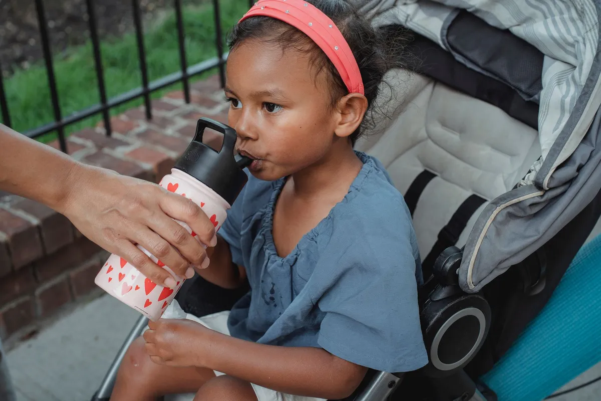 Child drinking from a water bottle with a straw