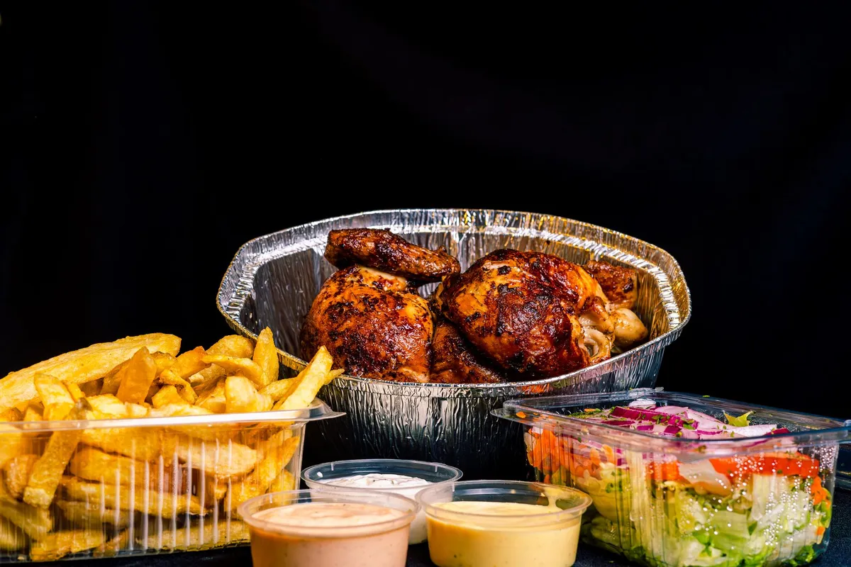 Whole chicken turning on a rotisserie spit in a countertop oven