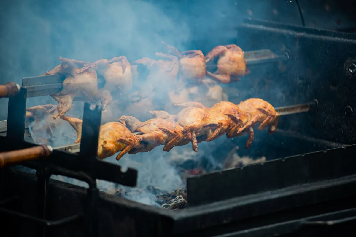 Pollo entero asándose en el espetón de un horno eléctrico