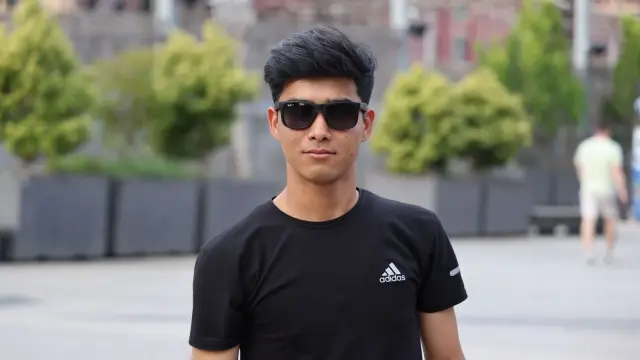 A person wearing black glasses on a city sidewalk