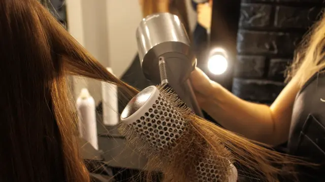 Woman straightening her hair with a flat iron in front of a mirror